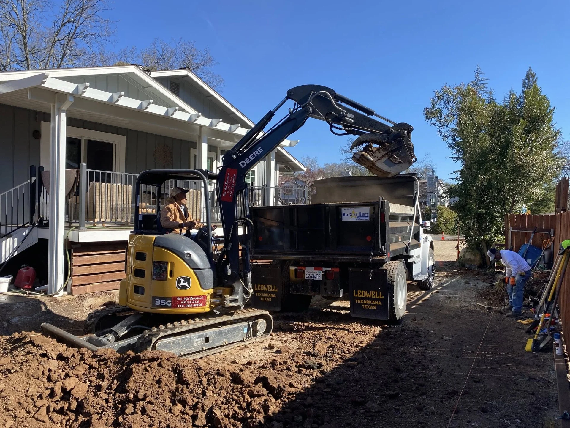 Excavator loading dirt for removal and haul-off at residential property in Northern California